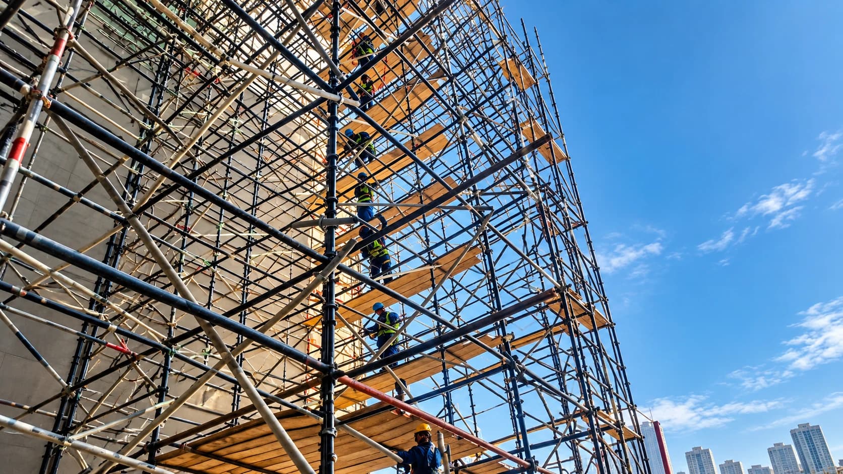 Workers on high-level scaffold platforms beside a building under construction
